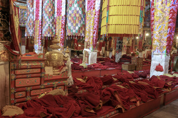 Red monk cloaks dagans lying folded in the temple in Drepung monastery interior near Lhasa, Tibet, Asia