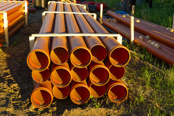 orange sewer pipes at a construction site. Underground orange plastic pipes. Stacked PVC orange...