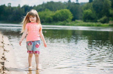 
Little happy girl walks along the river
