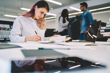  Concentrated female student preparing for examination in university library