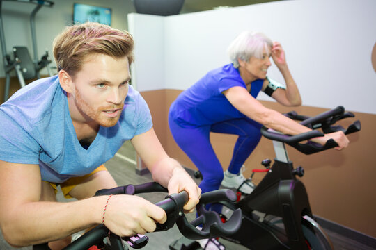 older woman and young man doing bike in gym