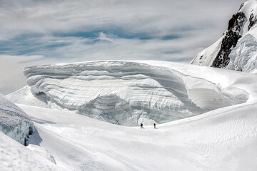 two climbers go in danger under a large glacier 