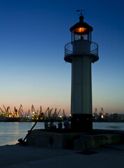 Sea lighthouse and passing boat at sunset over the port of Varna, Bulgaria.
