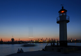 Sea lighthouse and passing boat at sunset over the port of Varna, Bulgaria.