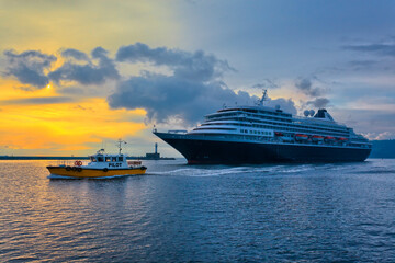 Cruise ship leaves the port, accompanied by a pilot boat.