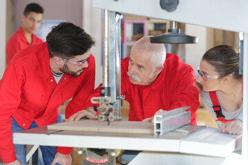 professional teacher showing carpentry machinery to students