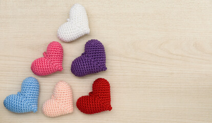 Colorful crochet hearts on a wooden background.