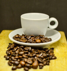 White coffee cup with coffee beans on wooden surface.