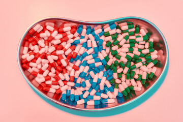 Creative flat lay, top view of different pills, capsules lying in metal box on a pastel pink background. Health care, vitamins and treatment concept