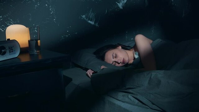 Close up of a Woman Sound Asleep in Cozy Bed with Dark Bed Covers. Dark-Haired Caucasian Woman Sleeping Well in Industrial Loft Bedroom.