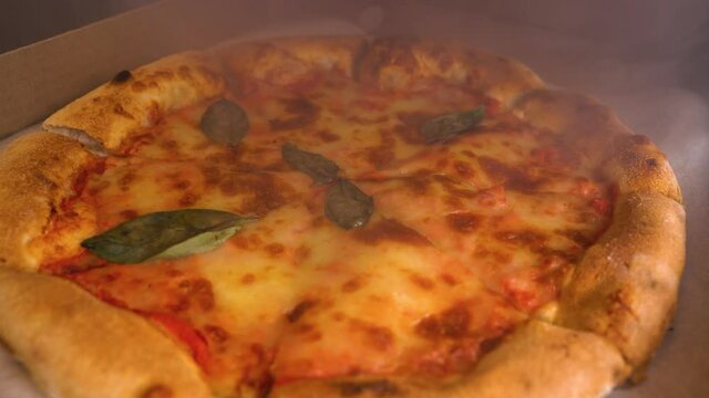 Opening box with pizza with a steam. Fresh pizza is in the box with smoke