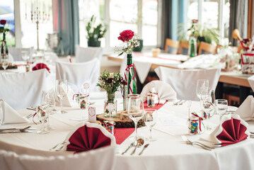 White color arrangement festive table decoration. Red rose flower in decorated high glass vase and arrangement of glassware. Celebration, wedding