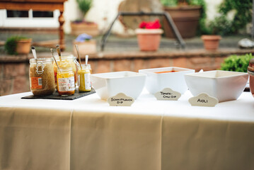 Table with various sauces and dips in glasses and white square bowls. Translation: Schnittlauch means chives. Celebration, party, birthday or wedding