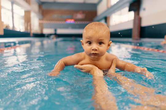 Young Mother And Her Baby Enjoying A Baby Swimming Lesson In The Pool. Child Having Fun In Water With Mom