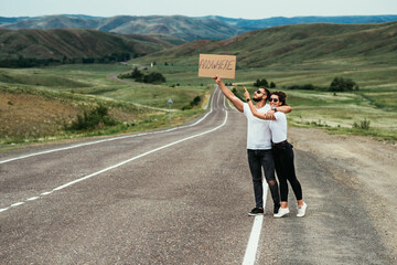 A man and a woman are hitchhiking. A young couple goes hitchhiking around the country. Free hitchhiking trip. A lover who travels free by hitchhiking. The couple goes traveling. Copy space