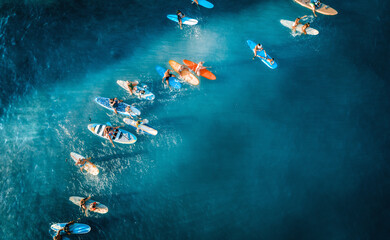 Aerial photo of big group of surfers paddle out together to support 