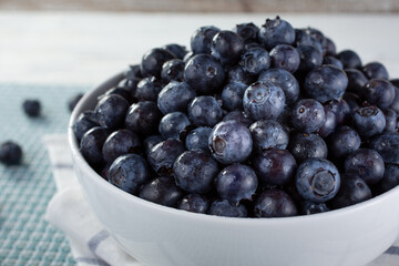 A closeup view of a bowl of blueberries, in still life setting.