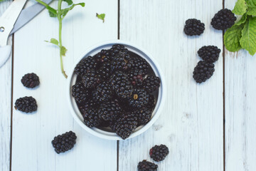A top down view of a bowl of blackberries, in a still life setting.