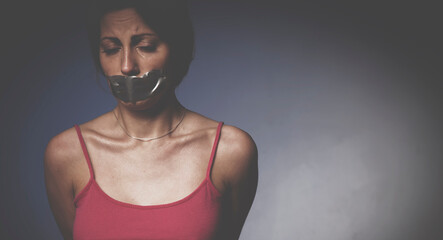 Pain, violence concept. Psychological portrait of depressed young woman with  mouth covered with a plaster. Free copy space for design or text.