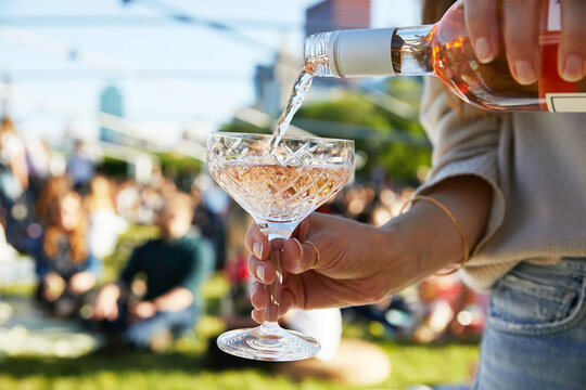 Pouring a sparkling wine in the sun at an outdoor festival.