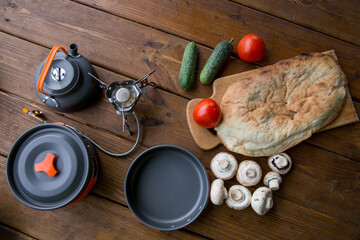 tourist gas burner, utensils, cucumber, tomato and pita standing on the table. Kitchen on the campsite