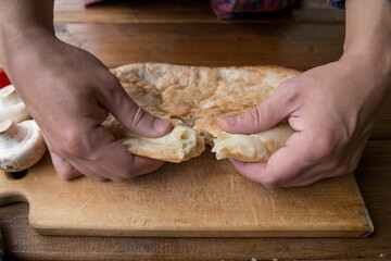 man breaks pita bread with his hands on a picnic at the campsite