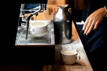 Woman preparing an espresso coffee at a coffee grinder in a restaurant