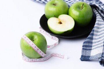 green apple with measuring tape on white background, healthy food concept
