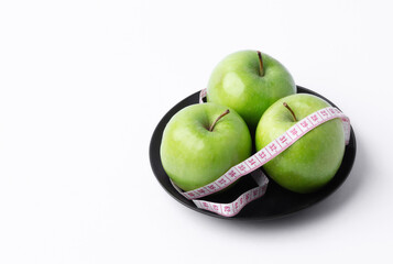 green apple with measuring tape on white background, healthy food concept