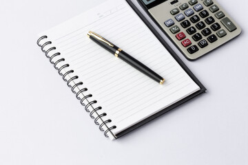 Pen, calculator on notebook close up on white background