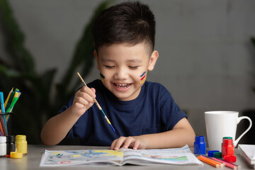 Happy little kid at the table draw with water color Learning and education of kid.