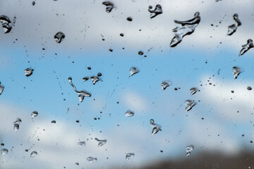 water droplets on the windshield with blue sky and white clouds