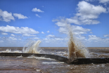 Sky with clouds and waves hitting the shore