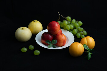 Various fresh fruits on black background.Red nectarine in white dish and yellow peach on black background