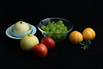 Various fresh fruits on black background.Red nectarine in white dish and yellow peach on black background