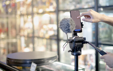 Male hand is shooting a video using gimbal and smart phone on tripod for live about the product for sell ans show the details of products