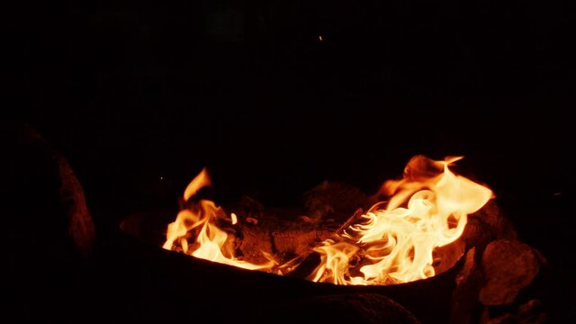 Flames from campfire burning at night, close-up of flames burning in slow motion on black background