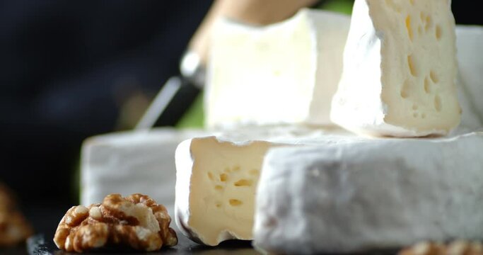 Pieces Camembert cheese with walnuts and grapes slowly rotate.