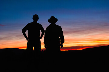 Fototapeta na wymiar Silhouetted hikers pause to observe the sunset
