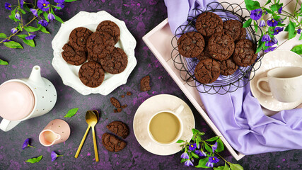 Serving freshly baked double chocolate chip homemade cookies on pink tray with tea and coffee, creative concept flat lay. Top view overhead.