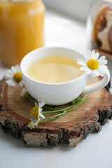 Cup of herbal tea with chamomile daisy flowers on wooden plate, concept of calming tea party, antistress herbal beverage, alternative medicine, remedi prevention