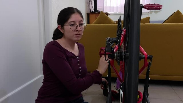 Young woman fixing a road red bicycle in an apartment.