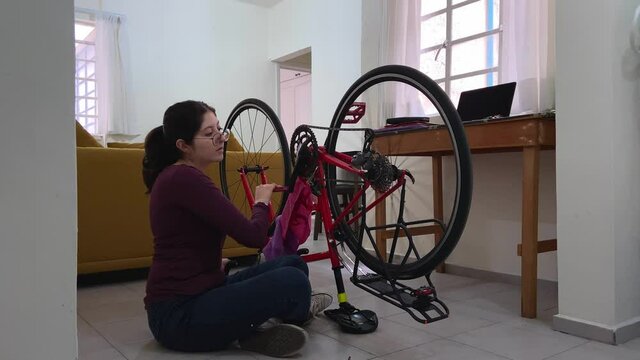 Young woman fixing her bicycle in an apartment.