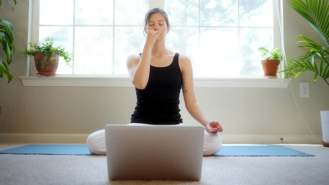 Young female yogi teaches an online remote yoga class while in isolation