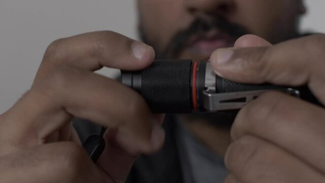 Close Up Hands Screwing On Battery Cap On Portable LED Torch. Low Angle