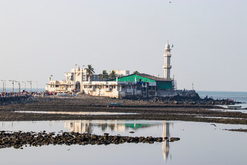 Fototapeta premium the reflection of Haji Ali Dargah, a mosque and dargah (tomb) or the monument of Pir Haji Ali Shah Bukhari located on an islet off the coast of Worli in the southern part of Mumbai India