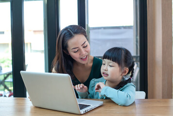 Mother and girl play computer at home