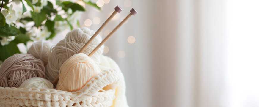 Knitted white and beige fabric. Woolen and cotton yarn lies in a basket. Glasses lie on a white wooden background.