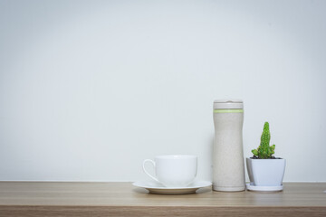 Coffee cup and thermos bottle on table.