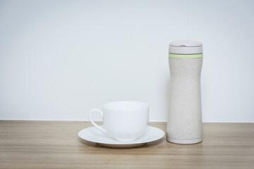 Coffee cup and thermos bottle on table.